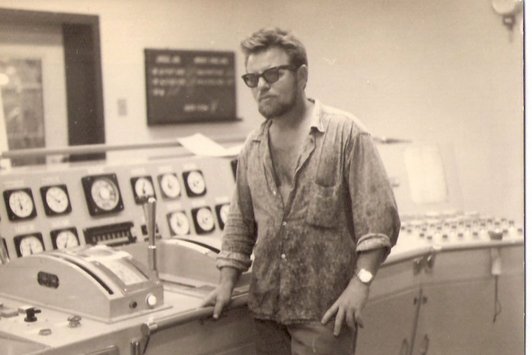 Ein junger Mann mit Bart und Sonnenbrille steht in einem Maschinenraum