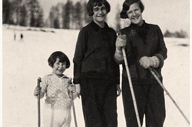 Ein kleines Mädchen fährt Ski mit ihren beiden älteren Schwestern