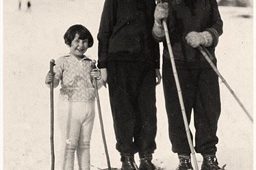 Ein kleines Mädchen fährt Ski mit ihren beiden älteren Schwestern