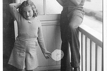 Ein junger Mann spielt Querflöte am Balkon, daneben seine kleine Schwester