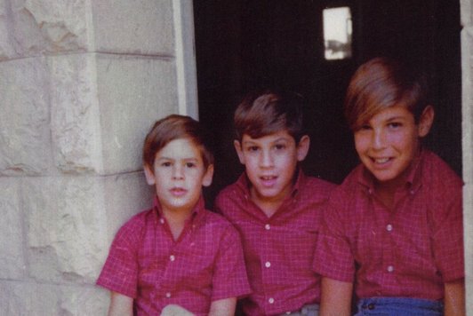 Drei junge Kinder sitzen in einem Türrahmen