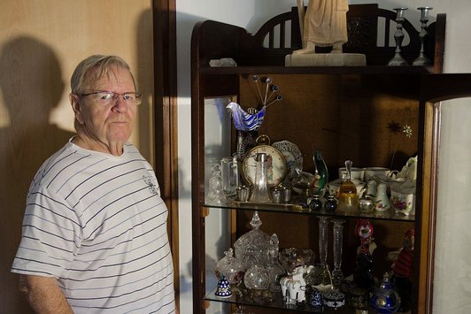 Ein älterer Herr steht neben einem Geschirrschrank