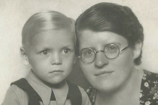 Ein Portraitfoto eines jungen Buben und einer Dame, der Bub hält ein Kuscheltier in den Armen