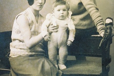 Ein Baby wird von einer Frau gehalten, eine weitere Frau ist im Bild zu sehen