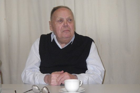 Ein älterer Mann sitzt zu Tisch