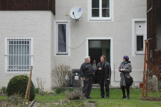 Drei Personen befinden sich im Hof eines Hauses