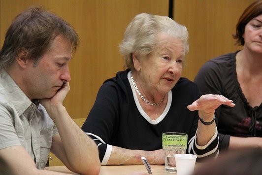 Eine ältere Dame spricht an einem Tisch