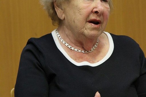 Eine ältere Frau spricht an einem Tisch