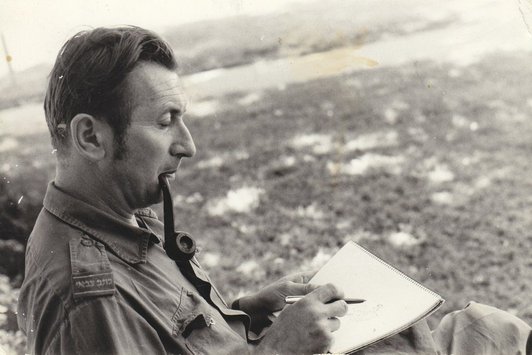 Ein uniformierter Mann raucht Pfeife und arbeitet in einem Notizblock