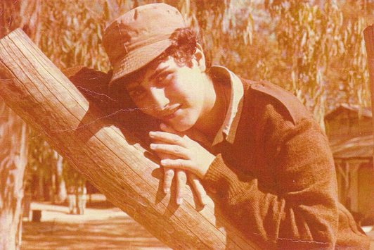 Eine junge Frau lehnt sich an einen Baumstamm