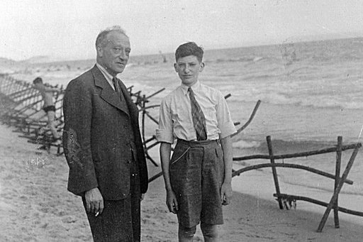 Ein Bursche und dessen Vater stehen an einem Strand