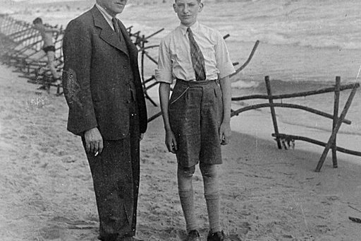 Ein Bursche und dessen Vater stehen an einem Strand