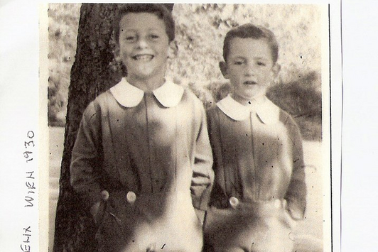 Zwei junge Burschen stehen vor einem Baum und lachen