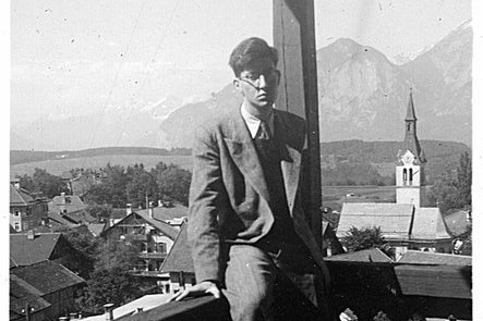 Ein junger Mann sitzt auf dem Geländer eines Balkons