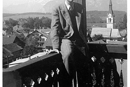 Ein junger Mann sitzt auf dem Geländer eines Balkons