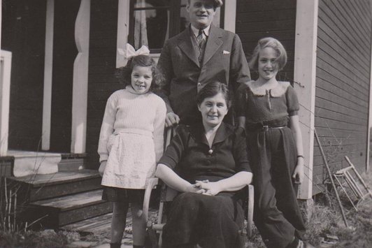 Vier Pesonen stehen vor dem Eingang eines Hauses