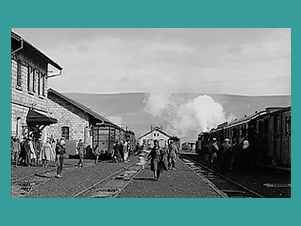 Eine Ansicht eines Bahnhofs, einige Personen sind im Bild zu erkennen