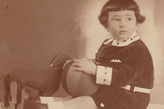 Ein Kleinkind ist mit Hunde-Kuscheltier und Spielzeugball zu sehen