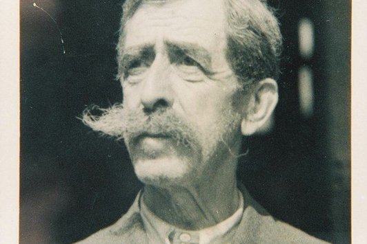 Eine Portraitaufnahme eines älteren Herrn mit markantem Schnauzer