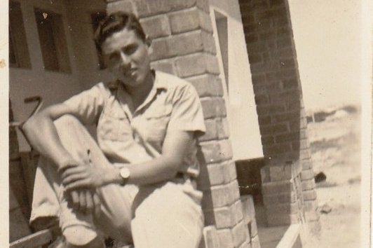 Ein Mann lehnt an einer Fassade